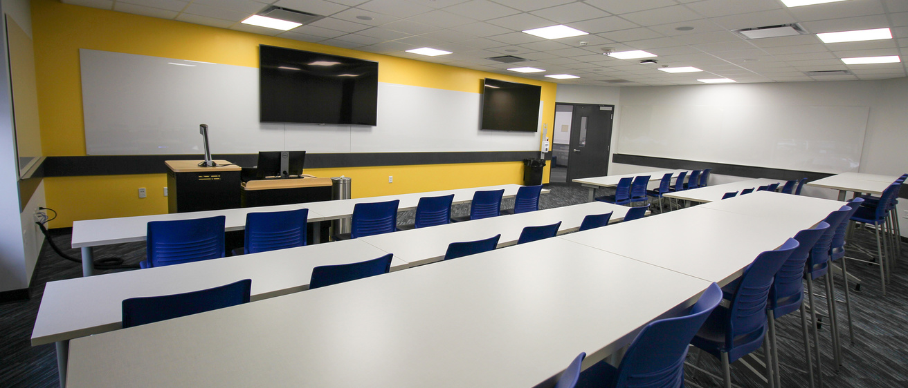 image of classroom with long white tables and blue chairs